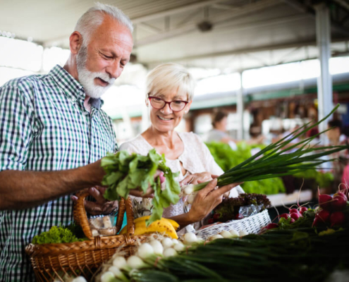 An elderly couple checking out produce at a San Diego farmers market