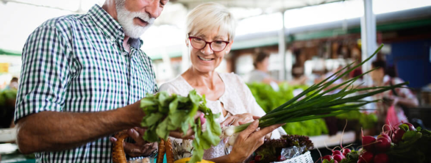 An elderly couple checking out produce at a San Diego farmers market