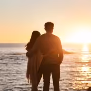 A couple watching the sunset on the beach, one of the most romantic things to do in San Diego