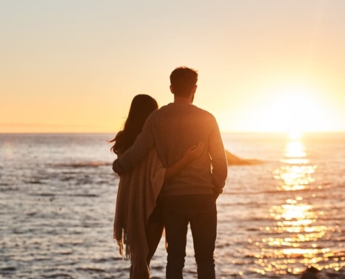 A couple watching the sunset on the beach, one of the most romantic things to do in San Diego