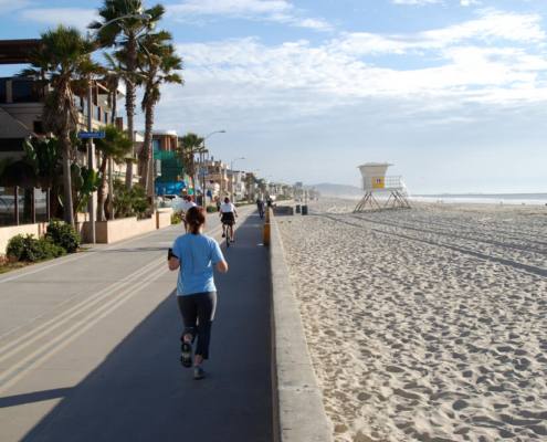 A person running on the Mission Beach boardwalk, one of the top things to do in the area