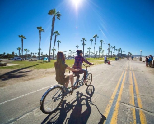 Girls riding a tandem bike on the Mission Beach Boardwalk in San Diego