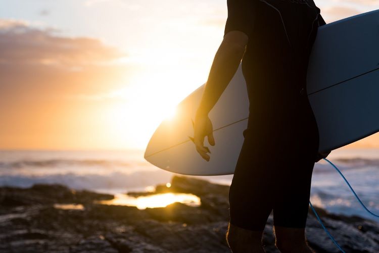 Surfer and surf board with the ocean in the background in San Diego