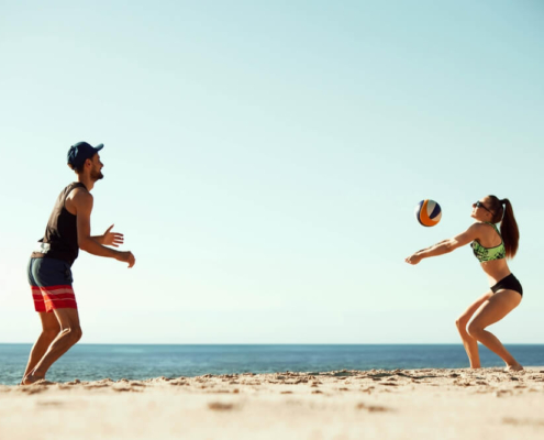 A man and woman playing beach volleyball on a beach in San Diego
