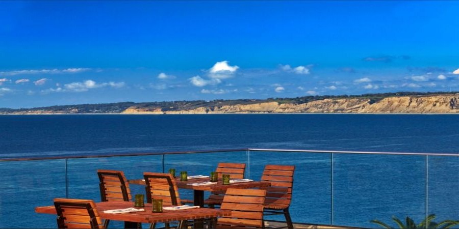 Oceanfront dining terrace at Duke's La Jolla with panoramic views of the Pacific and Torrey Pines cliffs, near Bluewater Vacation Homes rentals